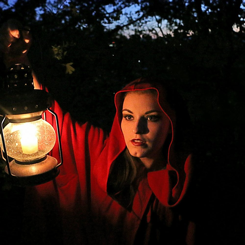 fairytale-portrait-of-woman-in-red-hood-holding-lighted-lantern-as-she-enters-dark-woods-.jpg